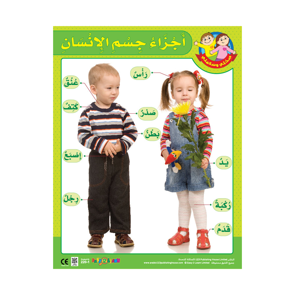 A colorful wall chart in Arabic featuring body parts with corresponding English translations, displayed in a classroom setting with a young boy and girl posing next to it.
